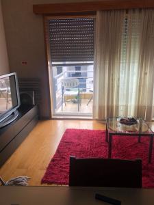 a living room with a tv and a red rug at Apartamento Parque Urbano in Ponta Delgada