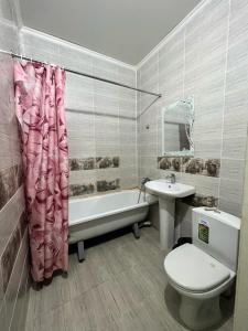 uma casa de banho com um WC, uma banheira e um lavatório. em Гостиница NUR em Aralʼsk