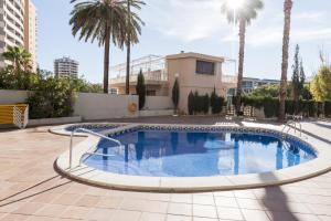 a swimming pool with palm trees and a building at Apartamentos Michel Angelo Benidorm in Benidorm