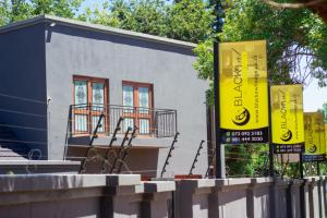 a building with two yellow signs in front of it at Black Owl Lodge in Kempton Park