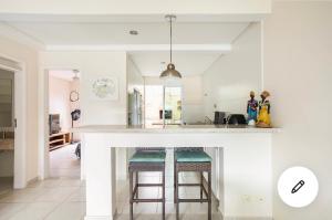 a kitchen with a white counter and stools at Casa charmosa Juquehy in Juquei