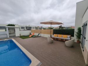 a patio with an umbrella and a pool at Meco Beach Villa in Sesimbra