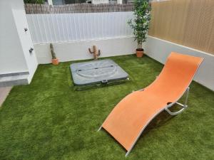 an orange chair and a mattress in a room with grass at Meco Beach Villa in Sesimbra +35 photos