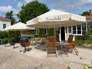 a patio with a table and chairs under an umbrella at Vanha Ravintola Ölvin Suolatorilla - Vanhan Kanttorilan yhteydessä in Lovisa +22 photos