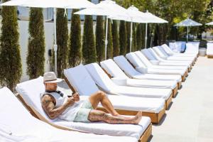 a man is laying on a row of white lounge chairs at The St Laurent Guest Rooms in Asbury Park