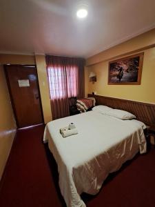 a hotel room with a large white bed and a chair at Hotel la casona in Huaraz