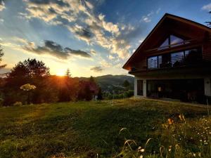 a house on a hill with the sunset in the background at Willa 桃 MoMo Szczawnica in Szczawnica