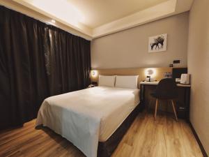 a bedroom with a bed and a desk with a chair at Hub Hotel Songshan Inn in Taipei