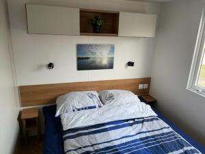 een slaapkamer met een bed met een houten hoofdeinde bij Chalet Lieblingsplatz in Lauwersoog