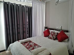 a bedroom with a large bed with red pillows at 1255 Palm Ridge Vipingo Estate Apartments in Kilifi +22 photos