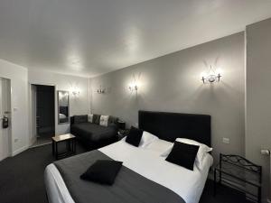 a bedroom with a large bed and a couch at Hotel Le Saint-Yves in Le Tréport
