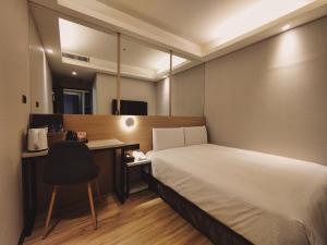 a bedroom with a bed and a desk and a chair at Hub Hotel Songshan Inn in Taipei