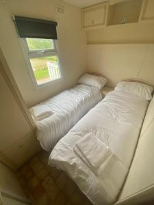 two beds in a small room with a window at Kestral Pet Friendly Caravan in Alford