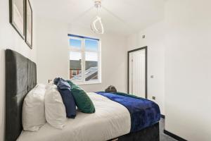 una camera da letto con letto, cuscini e finestra di Elegant Yorkshire Abode - Great Location - Sleeps 19 a Castleford