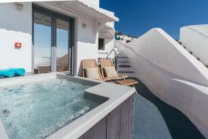 a hot tub on the balcony of a house at Aspa Caves in Oia