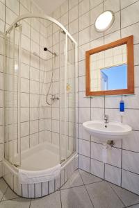 ein Bad mit einer Dusche und einem Waschbecken in der Unterkunft Hotelik Gołdap in Goldap