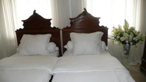 2 camas con sábanas blancas y un jarrón con flores en Apartment Dům U Černého beránka, en Praga
