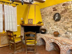 Habitación con 2 sillas y chimenea de piedra. en Casa Rural La Yedra, en Galve