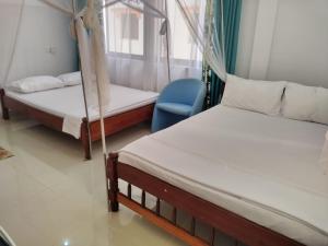 1 dormitorio con 2 camas y silla azul en 6 Park Retreat en Mombasa