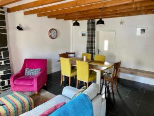 a dining room with a table and yellow chairs at Pen y Cwm in Penmachno