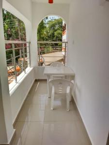 een witte kamer met een tafel en twee ramen bij 6 Park Retreat in Mombasa