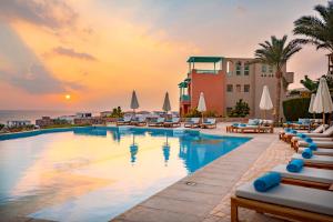 a pool at a resort with a sunset in the background at Zen Resort Sahl Hasheesh by TBH Hotels in Hurghada
