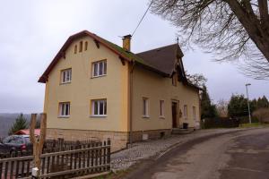 una casa amarilla con una valla al lado de una carretera en Apartmány Petra, en Hřensko