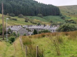 a group of buildings on a hill in a field at Pen y Cwm in Penmachno