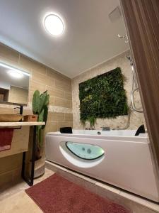 baño con bañera con una planta verde en la pared en Velours & Balnéo, en Saint-Nazaire