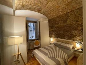 1 dormitorio con cama y pared de ladrillo en CASA ANTICA - antique apartment with private terrace, en Roma