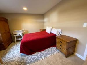 een slaapkamer met een bed met een rode deken en een wastafel bij Private basement bedroom with private bathroom, kitchen, and living room with large screen television in McCordsville
