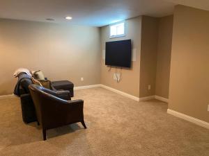 sala de estar con sofá y TV de pantalla plana en Private basement bedroom with private bathroom, kitchen, and living room with large screen television, en McCordsville