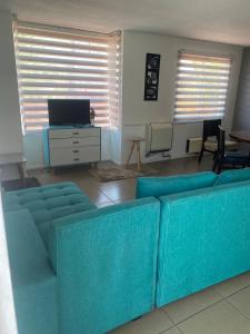 sala de estar con sofá azul y TV en Casa 3 habitaciones exclusiva valle lo campino, en Santiago