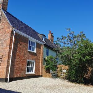 a brick house with chairs in front of it at Beehive Cottage in Beccles