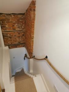 a stairway with a brick wall and a stair case at Beehive Cottage in Beccles