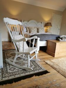 a bedroom with a white rocking chair and a bed at Beehive Cottage in Beccles
