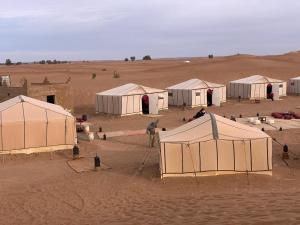 un grupo de tiendas en medio de un desierto en Couleur du désert en Mhamid