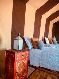 1 dormitorio con 2 camas y mesa con lámpara en Couleur du désert, en Mhamid
