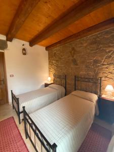 2 camas en una habitación con una pared de piedra en Su Lidone en Ozieri