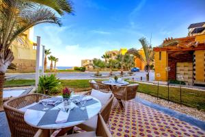 a patio with two tables and chairs and palm trees at Zen Resort Sahl Hasheesh by TBH Hotels in Hurghada