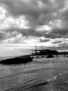 a black and white photo of a pier on the beach at La Via dei Trabocchi in San Vito Chietino +47 photos