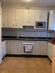 a kitchen with white cabinets and a microwave at Casa Ana in Benaoján