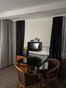 a room with a desk with a television and two chairs at T24 - Ihr Appartement mit Charakter in Sindelfingen