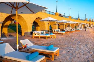 a row of lounge chairs and umbrellas on a beach at Zen Resort Sahl Hasheesh by TBH Hotels in Hurghada