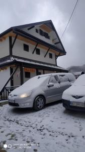 two cars parked in front of a building covered in snow at Vila Kula in Crni Vrh