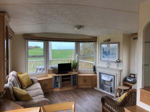 een woonkamer met een bank en een open haard bij Captivating 2-Bed static caravan in Holyhead in Llanfachraeth