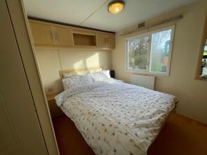 a bedroom with a bed with a white comforter and a window at Captivating 2-Bed static caravan in Holyhead in Llanfachraeth