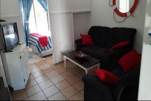 ein Wohnzimmer mit einem schwarzen Sofa und roten Kissen in der Unterkunft St Lucia Villa Mia 11 in St Lucia