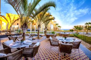 a restaurant with tables and chairs and palm trees at Zen Resort Sahl Hasheesh by TBH Hotels in Hurghada