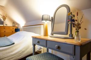 a bedroom with a bed and a dresser with a mirror at The Bolthole barn with wood-fired hot tub in Glentworth